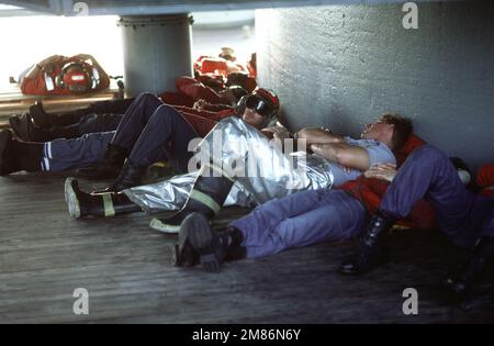 I membri di una festa contro il fuoco si rilassano sotto una delle torrette Mark da 7 16 pollici/50 a bordo della nave da guerra USS IOWA (BB-61). Paese: Oceano Atlantico (AOC) Foto Stock