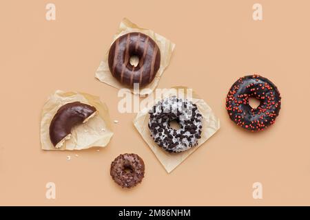 Parchments con diverse e deliziose ciambelle su sfondo beige Foto Stock