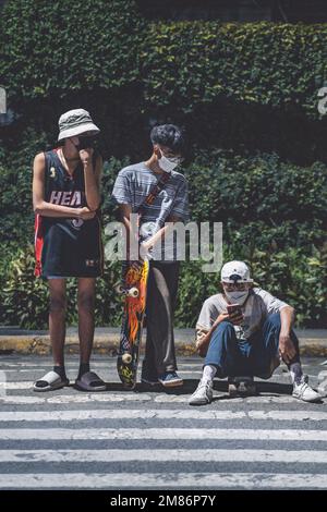 Un gruppo di giovani con skateboard in attesa sul lato di una strada nelle Filippine Foto Stock