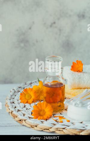 Una bottiglia di tintura di marigold di vaso o infusione con fiori freschi di calendula e tampone di cotone e si stende su uno sfondo bianco. Alternativa naturale alle erbe Foto Stock