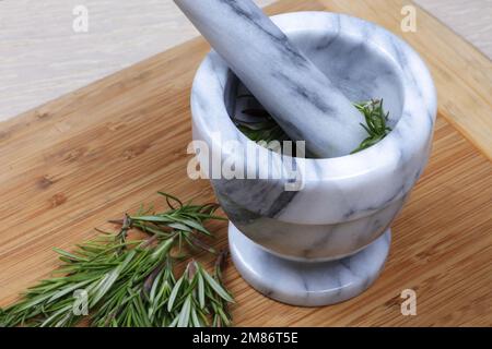 Erba di rosmarino in un mortaio e pestello dall'alto Foto Stock