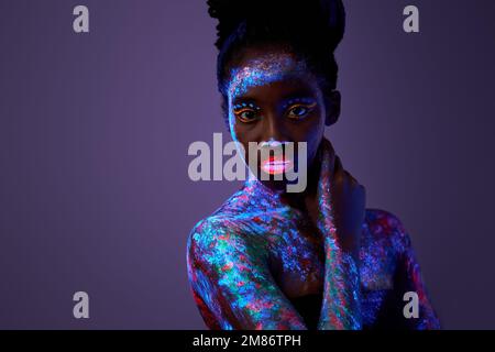 affascinante donna nera impeccabile tenere le mani sul collo non indossare abiti isolati su sfondo colorato neon viola, attraente pacifica signora con fluorescente Foto Stock