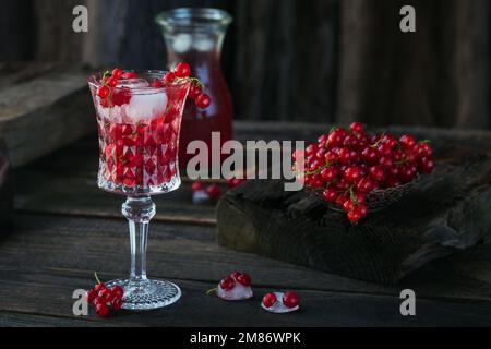 Drink estivo con vino bianco frizzante. Cocktail di frutta fresca fatta in casa o punch con champagne, ribes rosso, cubetti di ghiaccio e foglie di menta al buio Foto Stock