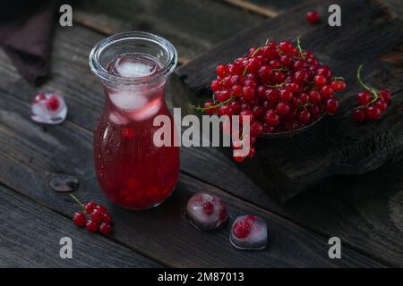 Drink estivo con vino bianco frizzante. Cocktail di frutta fresca fatta in casa o punch con champagne, ribes rosso, cubetti di ghiaccio e foglie di menta al buio Foto Stock