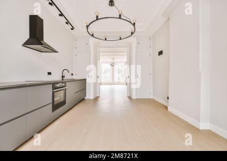 una cucina vuota con pareti bianche e pavimento in legno chiaro al centro della stanza è un chandel Foto Stock