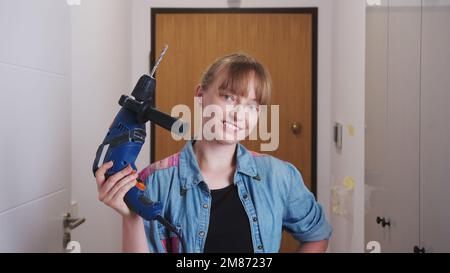 processo di riparazione, giovane donna allegra che tiene un trapano, donna indipendente che rinnova la sua casa. Foto di alta qualità Foto Stock