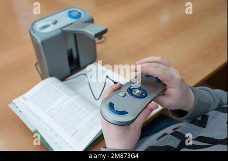 Un uomo ipovedente utilizza una macchina per la scansione e la lettura. Foto Stock