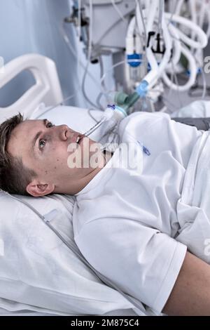 giovane uomo ferito sdraiato in letto stanza d'ospedale che riposa da dolore guardando in cattive condizioni di salute dopo aver subito un incidente nel concetto di assistenza sanitaria Foto Stock