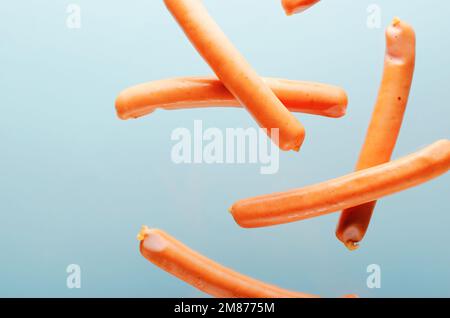 Levitazione delle salsicce, concetto di Flying Food, sfondo azzurro Foto Stock