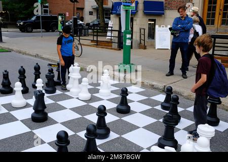 I bambini che giocano a scacchi in strada con pezzi di scacchi di grandi dimensioni e scacchiera in strada di Mile End a le Plateau Mont Royal.Montreal.Quebec.Canada Foto Stock