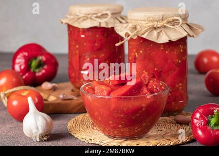 Peperoni dolci sottaceto con pomodori in ciotola e anche in due vasetti di vetro Foto Stock