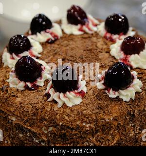 Un primo piano di una torta di foresta nera in un ristorante decorato con ciliegie Foto Stock