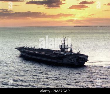 Una vista elevata del quarto porto della portaerei a energia nucleare USS THEODORE ROOSEVELT (CVN-71) in corso al tramonto. Paese: Oceano Atlantico (AOC) Foto Stock