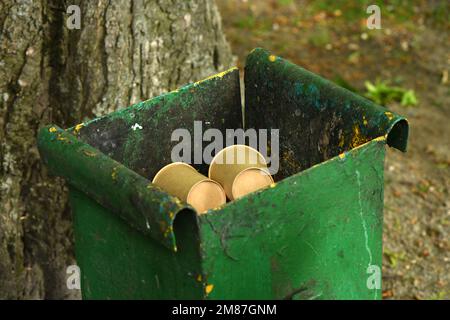 Vecchio cestino verde può. Nel cestino sono presenti due bicchieri di carta. Foto ad alta risoluzione. Messa a fuoco selettiva. Foto Stock