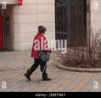 Nitra, Slovacchia - 01.06.2023: Una donna matura con bastoni da nordic walking cammina per le strade della città. Il concetto di uno stile di vita sano. Foto Stock