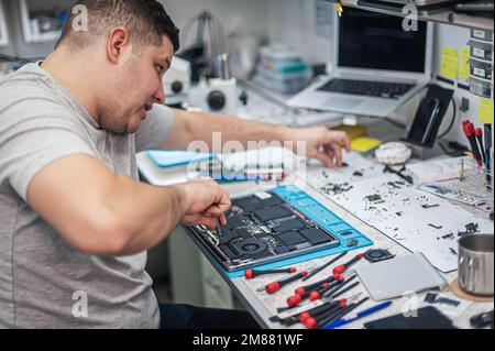 Supporto tecnico e risoluzione dei problemi relativi ai gadget. Manutenzione, riparazione, pulizia, manutenzione dei calcolatori. Officina di riparazione. Manutenzione hardware. Tecnici maschili Foto Stock