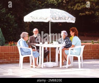 Residenti che hanno tè sul giardino terrazza di casa di cura, Surrey, Inghilterra, Regno Unito Foto Stock