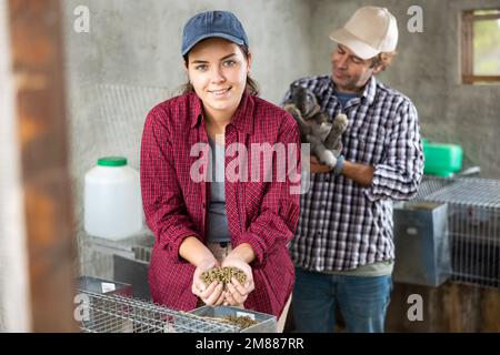 Affari di famiglia - l'uomo e la donna allevano conigli in fattoria Foto Stock