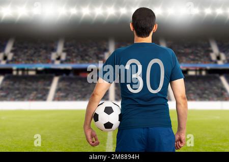 Immagine retrovista ritagliata di un giovane giocatore che tiene un pallone da calcio sotto le braccia a Paris.Rearview Foto Stock