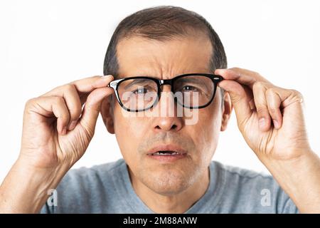 adulto con gli occhiali che stressano gli occhi perché non riesce a vedere, isolato con sfondo bianco Foto Stock