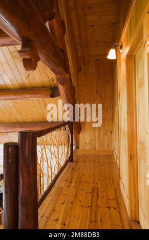 Ringhiera di diramazione di cedro e pavimenti in legno di pino rosso al piano superiore all'interno di una casa in legno di stile scandinavo. Foto Stock