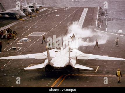 Gli equipaggi della piattaforma di volo sono in piedi mentre un aereo F-14A Tomcat è guidato su una catapulta durante le operazioni di volo a bordo della portaerei nucleare USS THEODORE ROOSEVELT (CVN-71). Paese: Sconosciuto Foto Stock