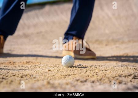 Dettaglio dei piedi di un uomo che gioca a golf, nel bunker che colpisce la palla con il bastone cuneo pitching Foto Stock