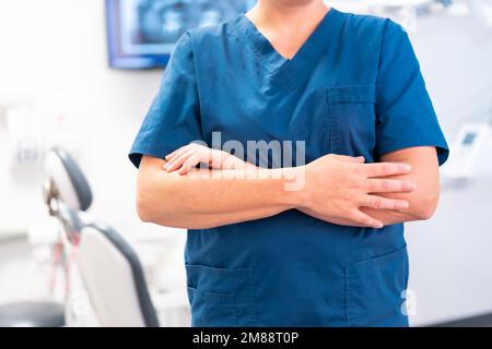 Clinica odontoiatrica, dentista caucasica irriconoscibile con braccia incrociate Foto Stock