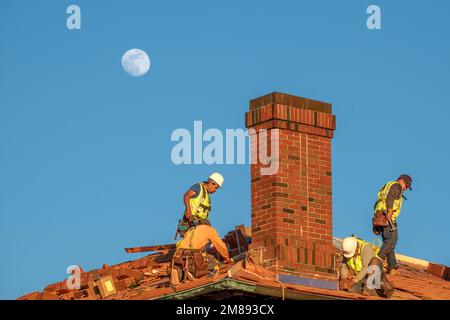 NEW ORLEANS, LA, USA - 4 GENNAIO 2023: I tetti sostituiscono le tegole su un tetto storico con la luna sullo sfondo Foto Stock