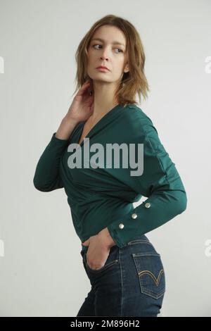 Foto studio di giovane modella femminile che indossa jeans skinny e camicia verde in cotone biologico Foto Stock