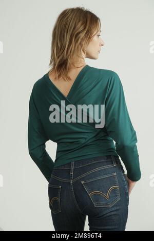 Foto studio di giovane modella femminile che indossa jeans skinny e camicia verde in cotone biologico Foto Stock