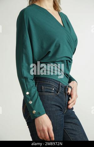 Foto studio di giovane modella femminile che indossa jeans skinny e camicia verde in cotone biologico Foto Stock