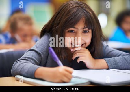 Amo imparare. Ritratto di una giovane ragazza che lavora al suo lavoro scolastico in classe. Foto Stock