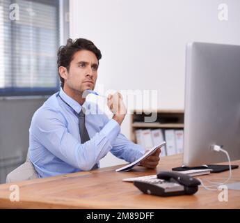 Pensare alle idee per un maggiore successo aziendale. Un serio giovane uomo d'affari che scrive nel suo notebook. Foto Stock