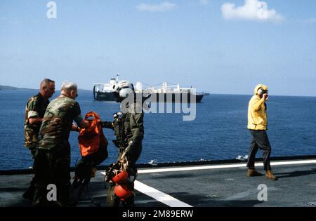 Un pilota distribuisce giubbotti salvagente prima di una trivella a bordo della nave logistica aerea USNS WRIGHT (T-AVB-3) come WRIGHT e la nave marittima di preposizionamento 2nd LT. JOHN P. BOBO (T-AK-3008), background, partecipa all'esercizio Ocean Venture '88. Oggetto/Serie: OCEAN VENTURE '88 Paese: Mar dei Caraibi Foto Stock