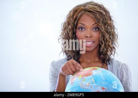SA dove vuole andare. Ritratto di un giovane insegnante che ti mostra un globo del mondo durante la geografia. Foto Stock