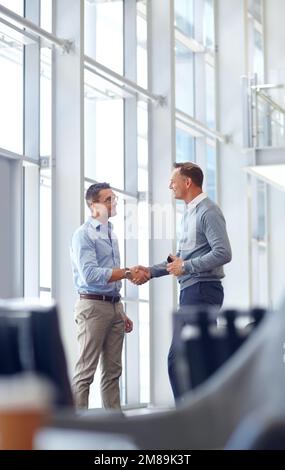 Uomini d'affari, stretta di mano o saluto nella hall dell'hotel, ufficio moderno o lounge dell'aeroporto in una riunione CRM. Sorridi, lavoratori felici o maturi che scuotono le mani Foto Stock