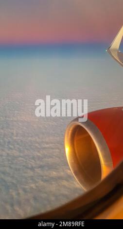 Vista dal porthole dell'aereo al bellissimo tramonto, al cielo blu e alle nuvole d'aria. PhotoView di alta qualità dal porthole dell'aeroplano al tramonto, al cielo blu e alle nuvole d'aria Foto Stock