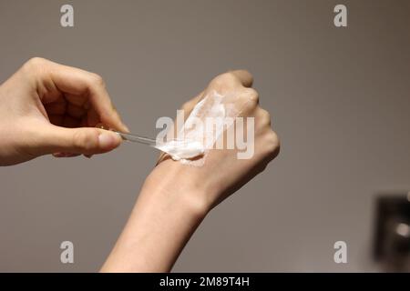 Applicazione di crema cosmetica sulle mani con spatola Foto Stock