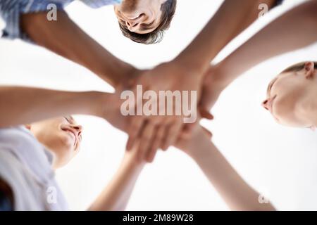 Il lavoro di squadra al suo meglio. Inquadratura a basso angolo dei colleghi che mettono insieme le mani in un gesto di spirito di squadra. Foto Stock