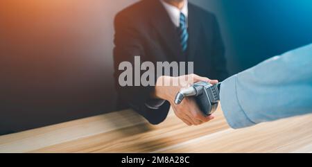 Mano di un uomo d'affari in un vestito che scuote le mani e fare a che fare con un robot droid. Concetto di innovazione nel business con intelligenza artificiale. Foto Stock