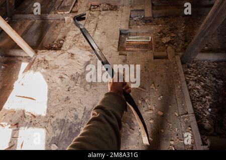 La mano maschio forte tiene un estrattore del chiodo, la demolizione della casa è in corso Foto Stock