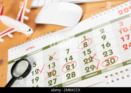 Calendario e promemoria per viaggi di lavoro, viaggi e vacanze. aliante sul desktop con aeroplano e lente d'ingrandimento e penna, tastiera. marcatura importante Foto Stock