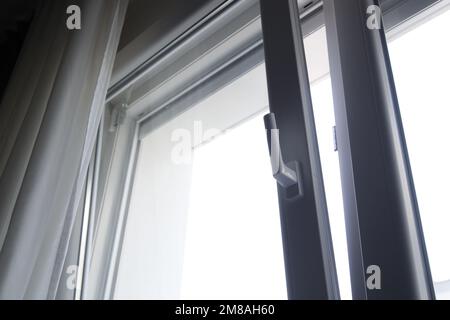 Inclina e gira la finestra in pvc appoggiata in alto per consentire una ventilazione controllata nell'appartamento, da vicino Foto Stock