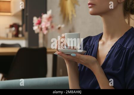Giovane donna rilassata godendo una tazza di caffè nel soggiorno, rilassante auto-cura giorno a casa concetto. Foto Stock