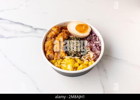 Una gustosa ciotola di poke con pollo e uovo sul tavolo di marmo Foto Stock