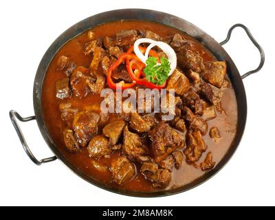 Carne fine - Goulash di manzo in una padella con pepe rosso isolato su sfondo bianco Foto Stock