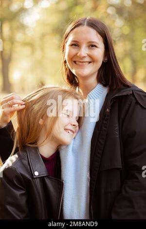 Ritratto di splendida famiglia di giovane donna e ragazza adolescente in piedi, abbracciando nel parco forestale in autunno. Foto Stock