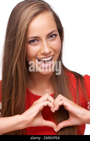 Donna, ritratto sorriso e forma delle mani del cuore, emoji per segno d'amore, felicità e sostegno su sfondo bianco. Modello viso, simbolo felice e cura di sé Foto Stock