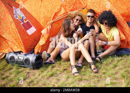 Campeggio con amici. un gruppo di amici seduti fuori dalla loro tenda e ridendo. Foto Stock